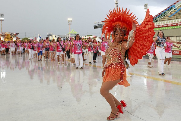 Foliã, vestida de fantasia laranja, dançando na avenida do sambódromo