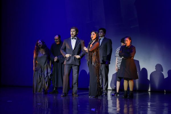Integrantes do Musical em momento de apresentação, em um cenário escuro