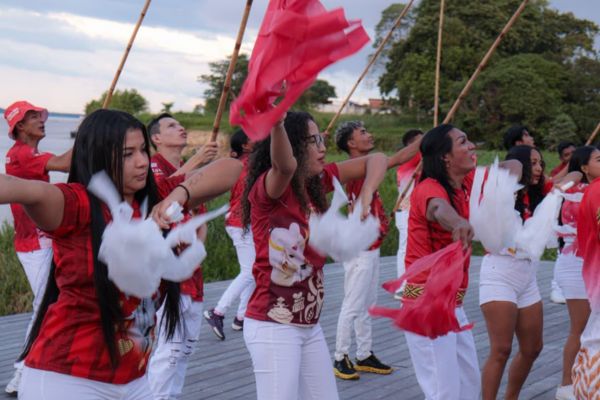 Integrantes do Comando Garantido, torcida oficial do Boi Garantido, estão com bandeiras e com sorriso no rosto, vestido com camisas vermelhas e calças brancas