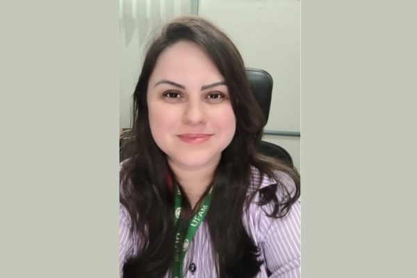 Uma mulher branca de cabelos pretos, sorrindo, a professora Marília Gabriela Gondim Rezende