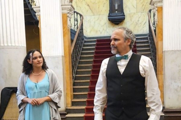 Os artistas estão em cena, no interior de uma casa antiga