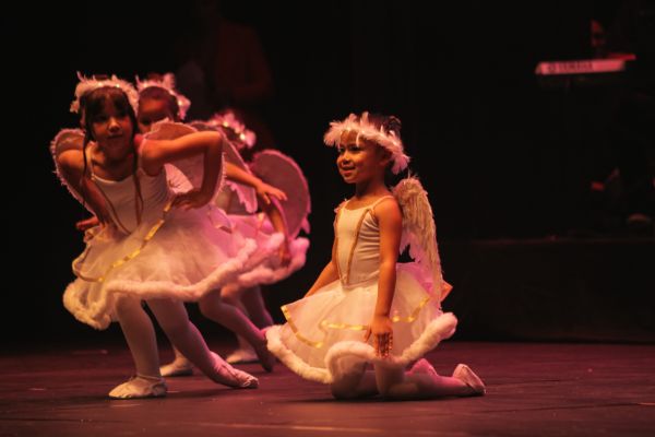 Crianças vestidas de anjo, em um palco, mo momento do espetáculo